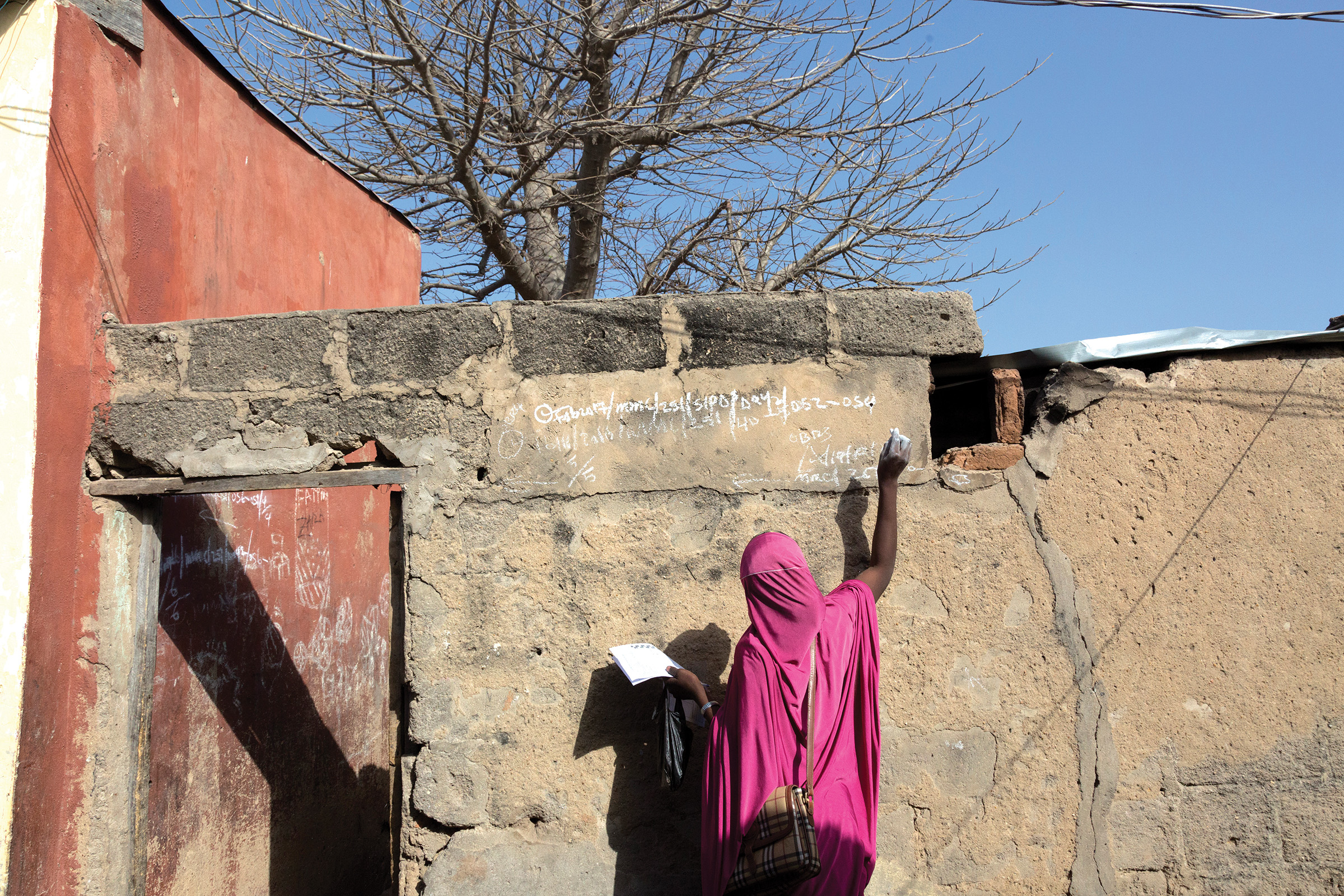 Volunteers vaccinate children in Maiduguri against polio, marking the houses they’ve visited. 